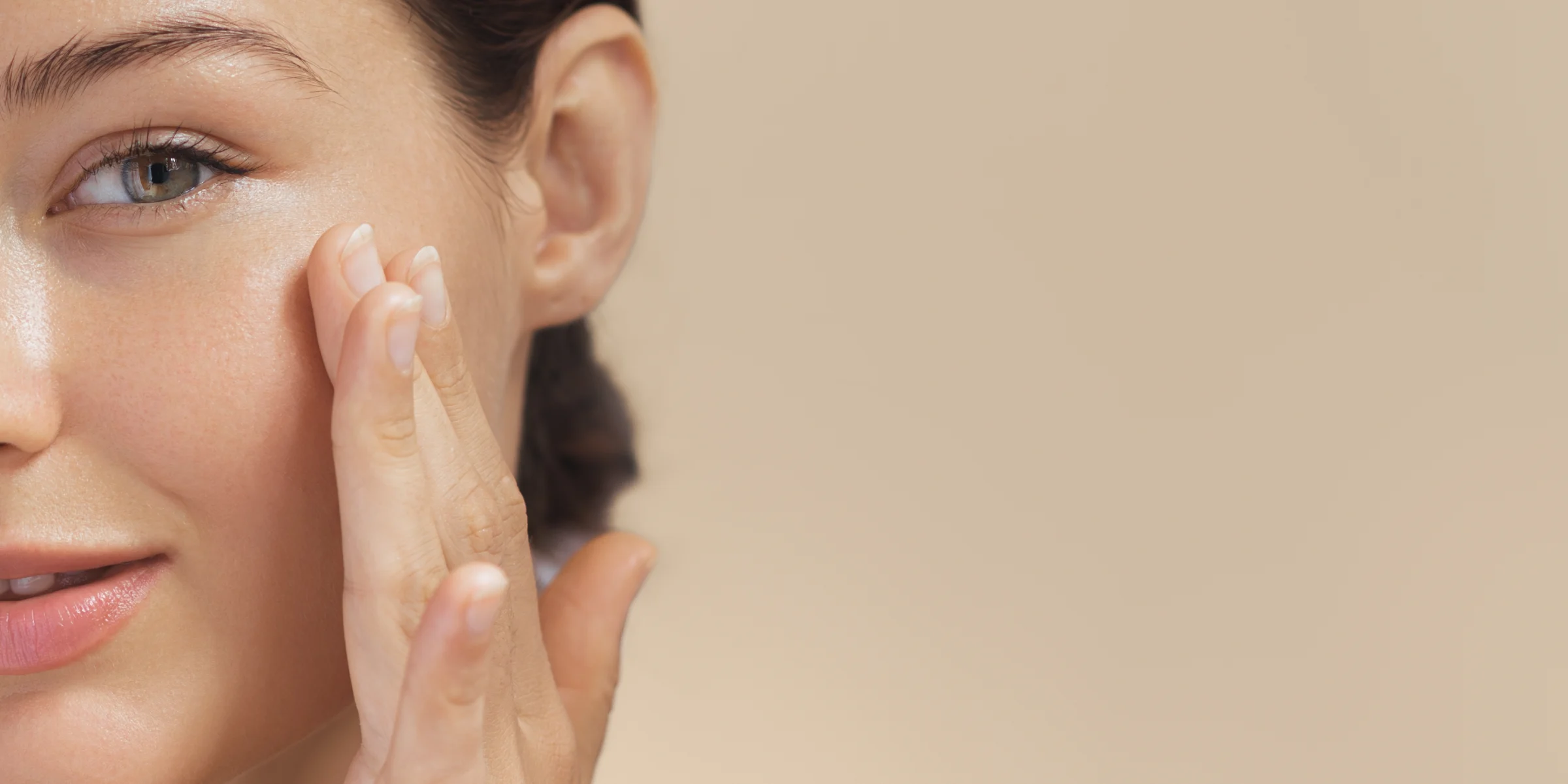 Woman with smooth, glowing skin touching her cheek