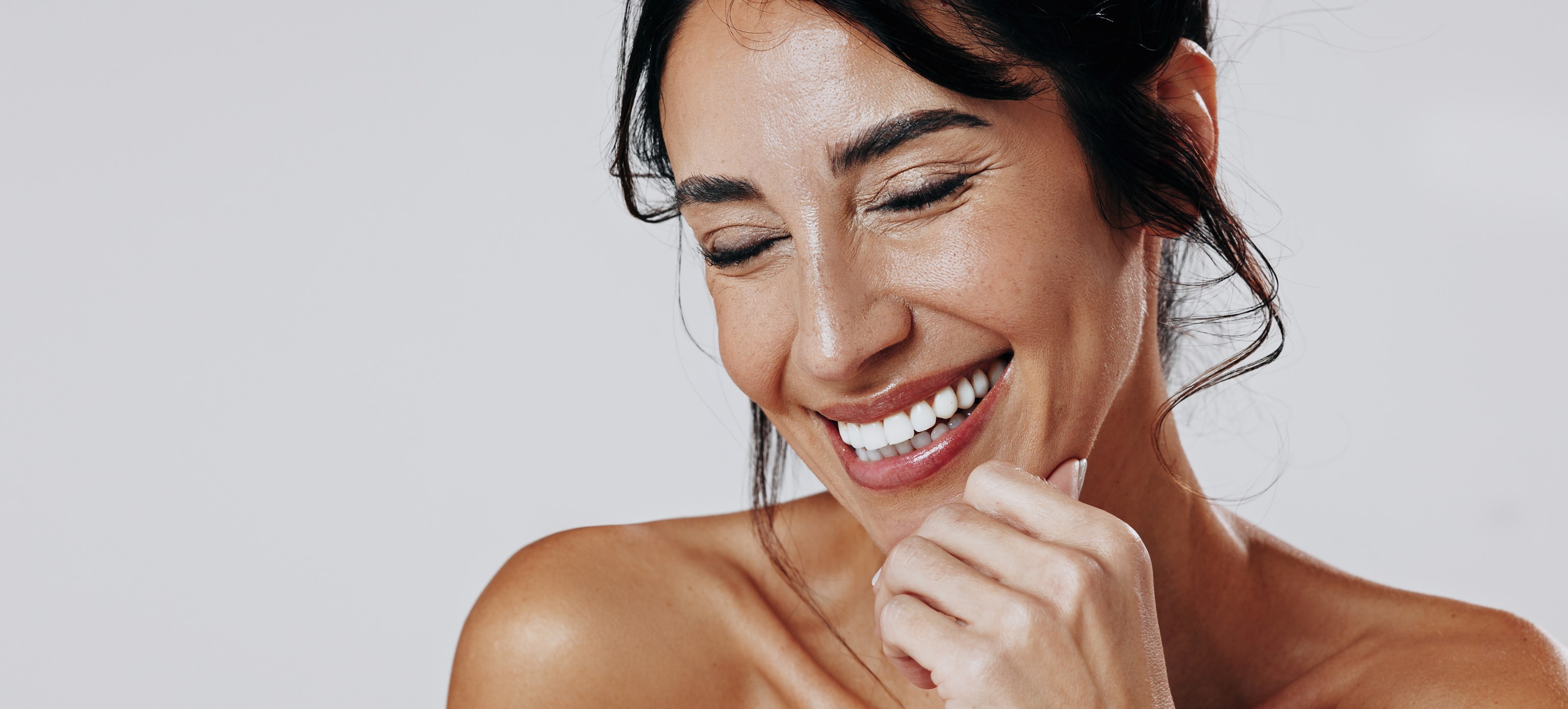 Smiling woman with glowing skin resting her chin on her hand